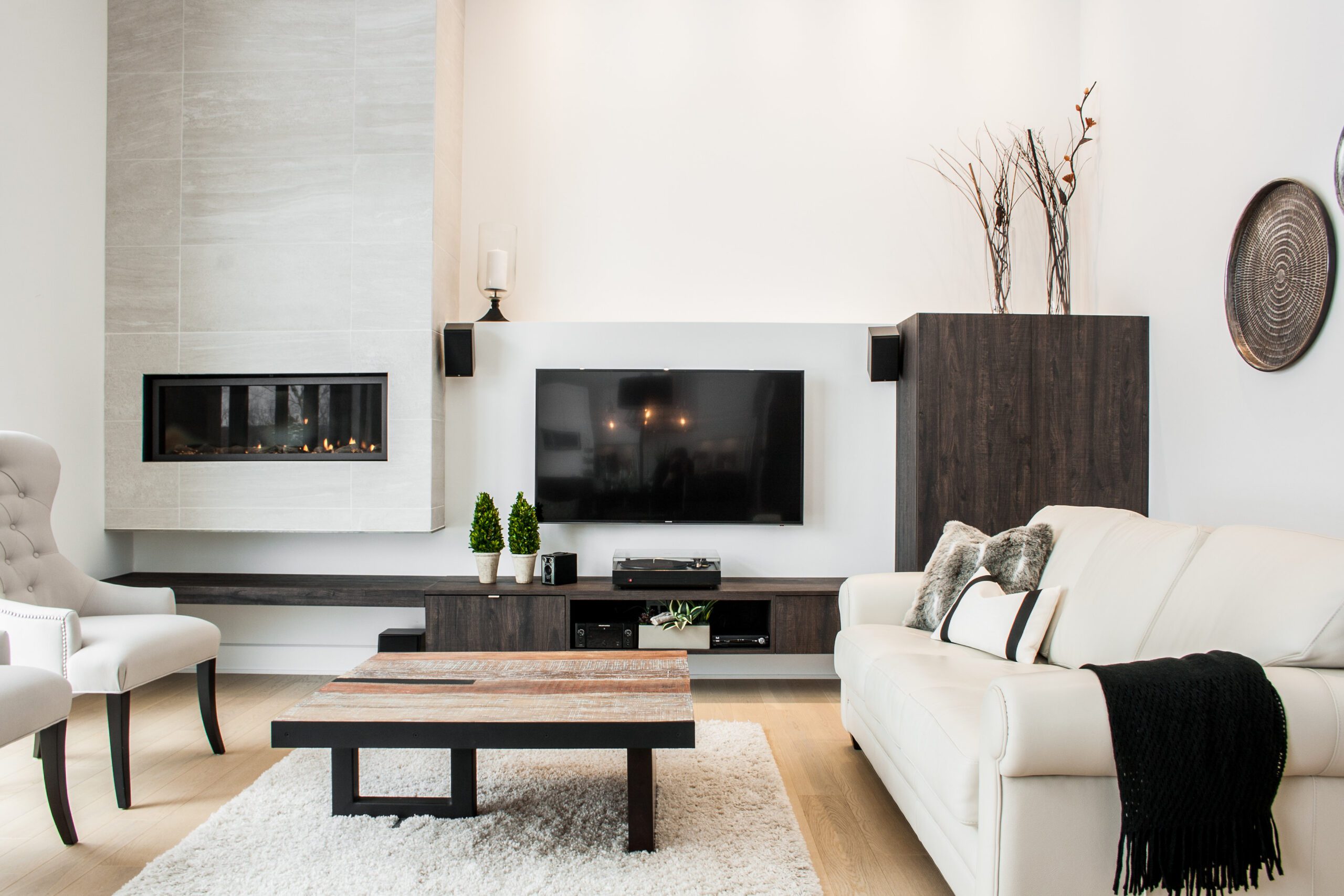 Salon avec téléviseur mural et table en bois près d'une causeuse greige