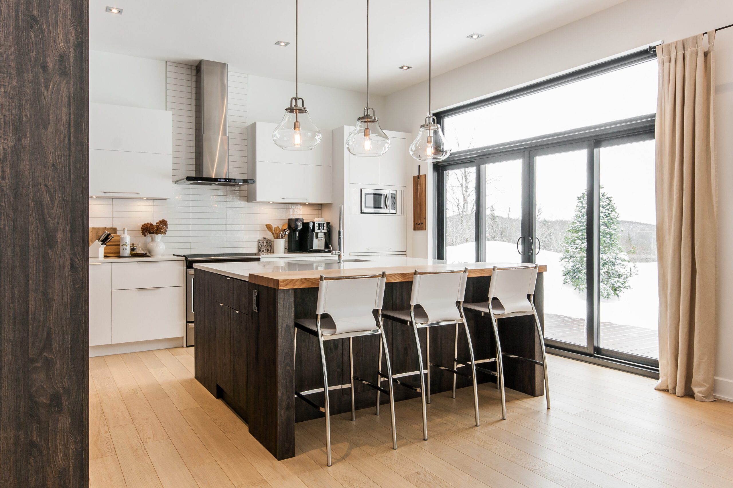 Cuisine moderne avec tabourets blancs et luminaires transaparents en verre