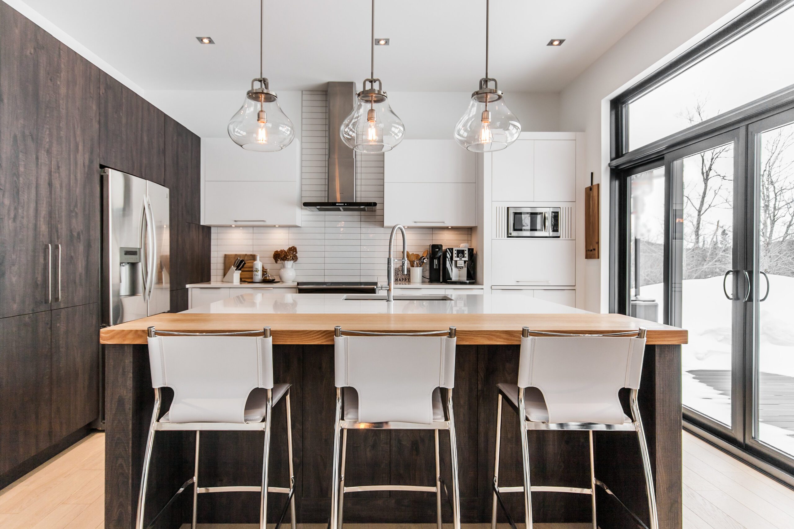 Cuisine moderne avec tabourets blancs et luminaires transaparents en verre