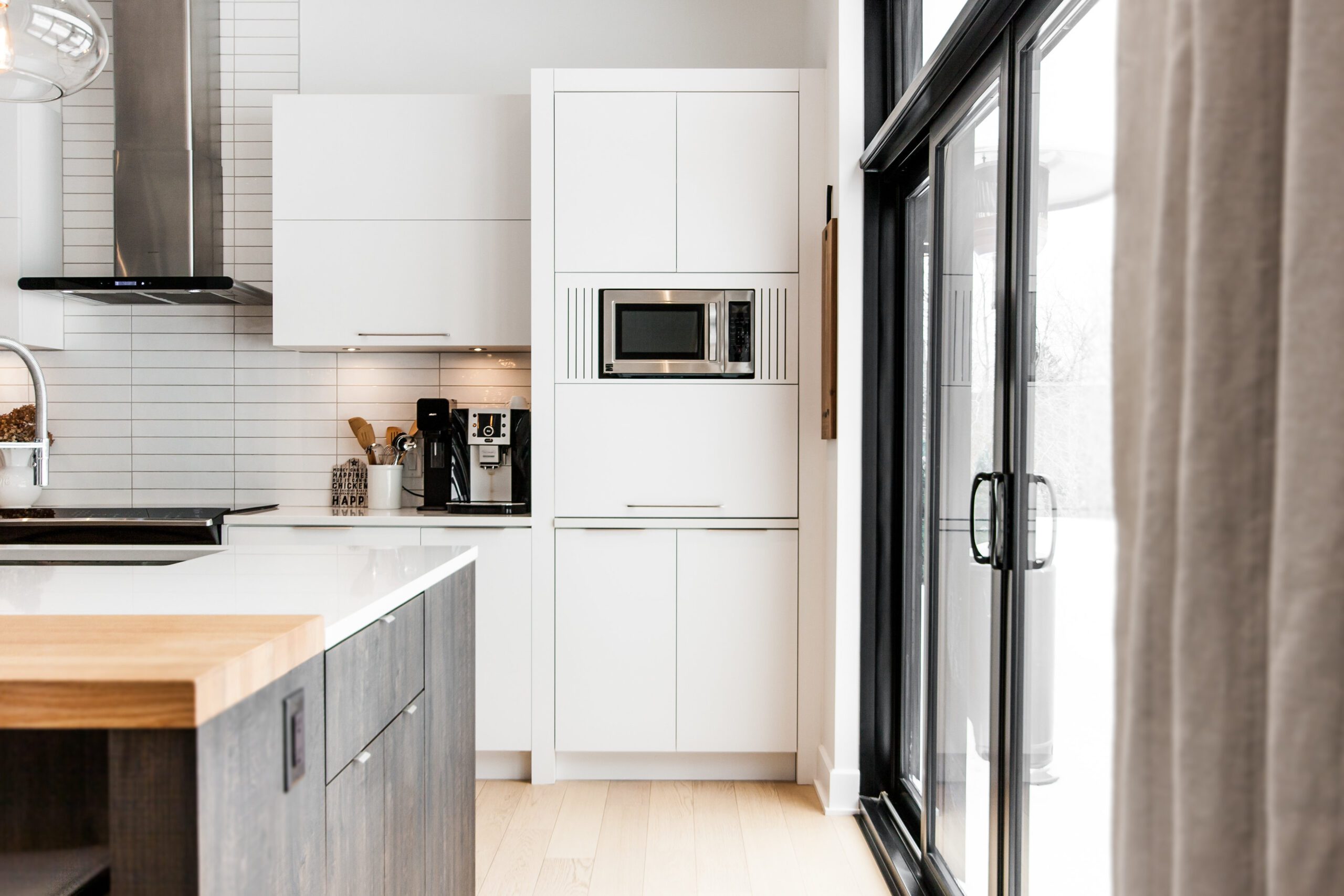 Cuisine moderne avec armoires blanches et bois et grande porte patio