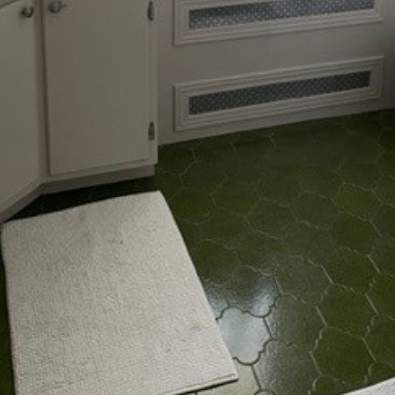 Plancher de salle de bain vieillot en céramique vert foncé avec tapis beige