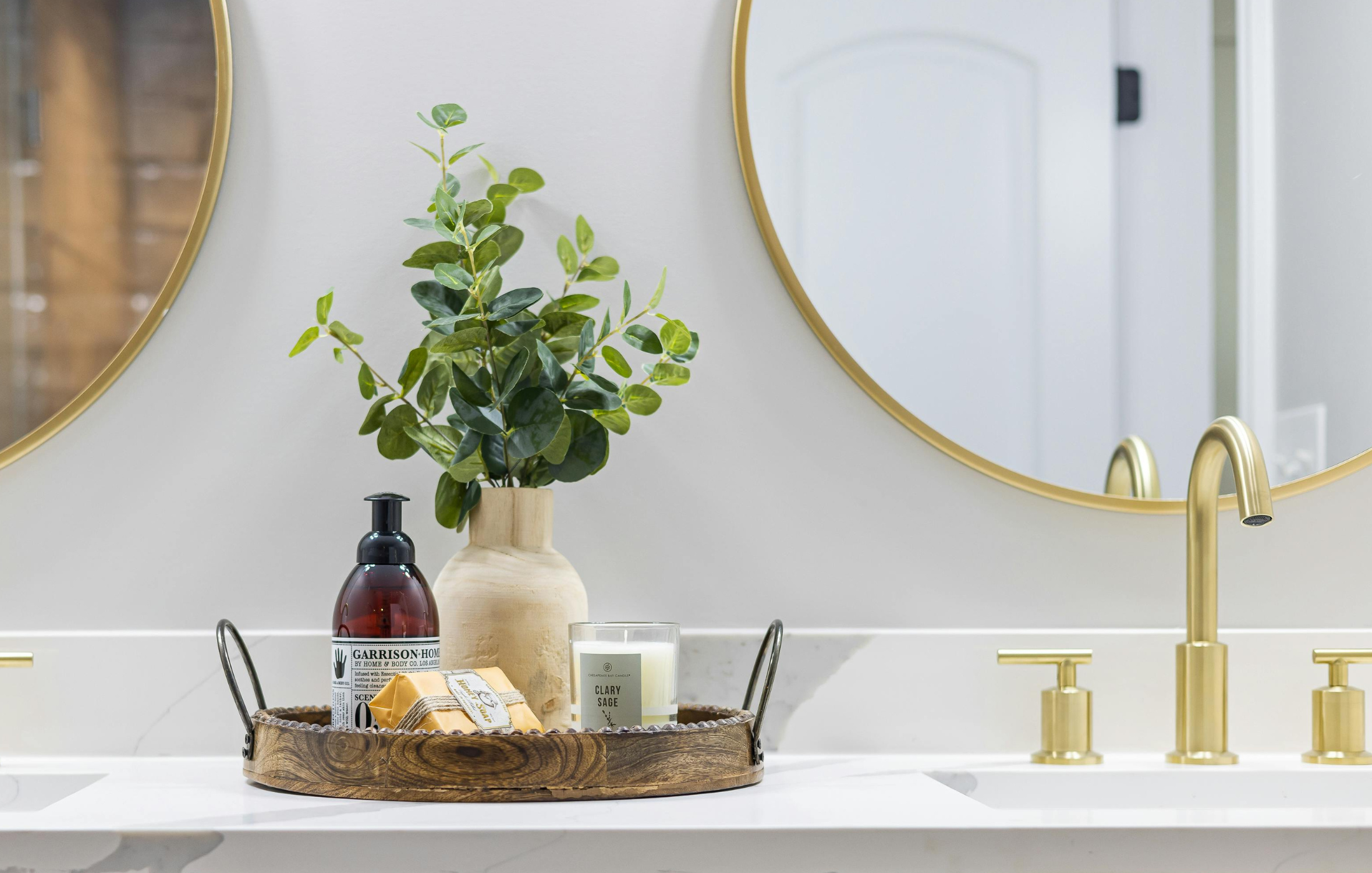 Vase d'eucalyptus sur comptoir de salle de bain avec robinet doré et miroir circulaire