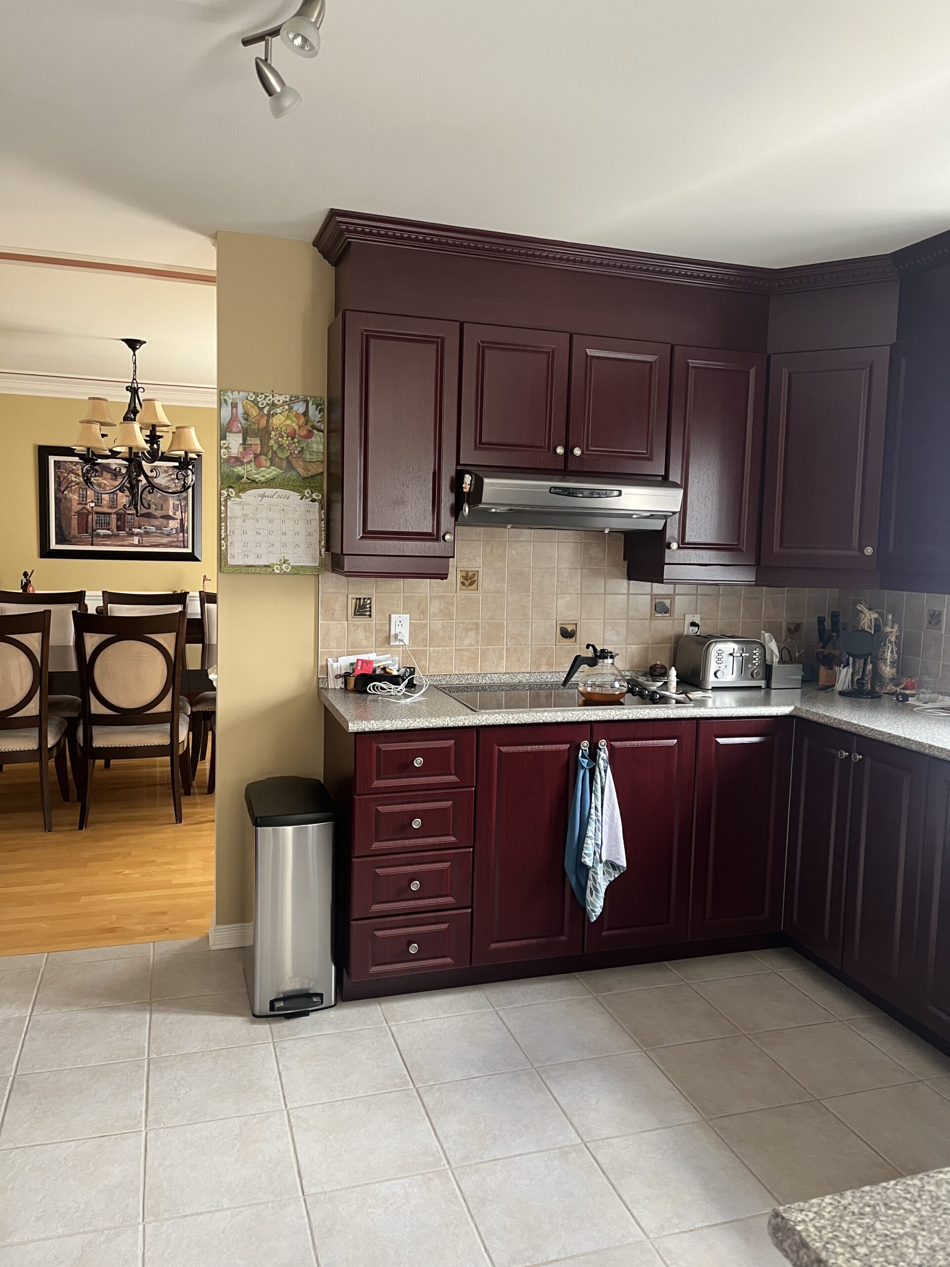 Cuisine rouge foncée avec vue sur une salle à manger jaune désuète