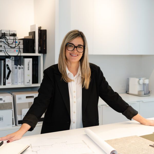 femme souriante devant comptoir de matériaux et de couleurs, designer