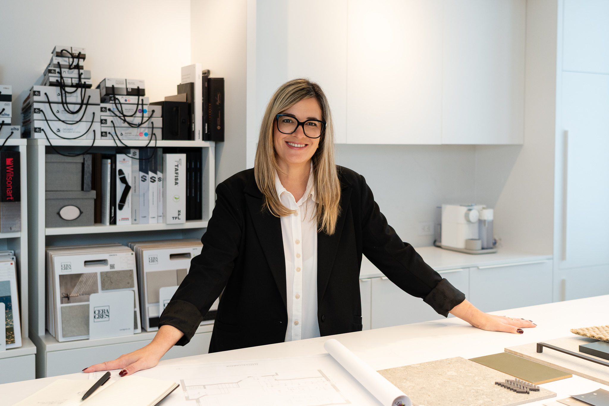 femme souriante devant comptoir de matériaux et de couleurs, designer