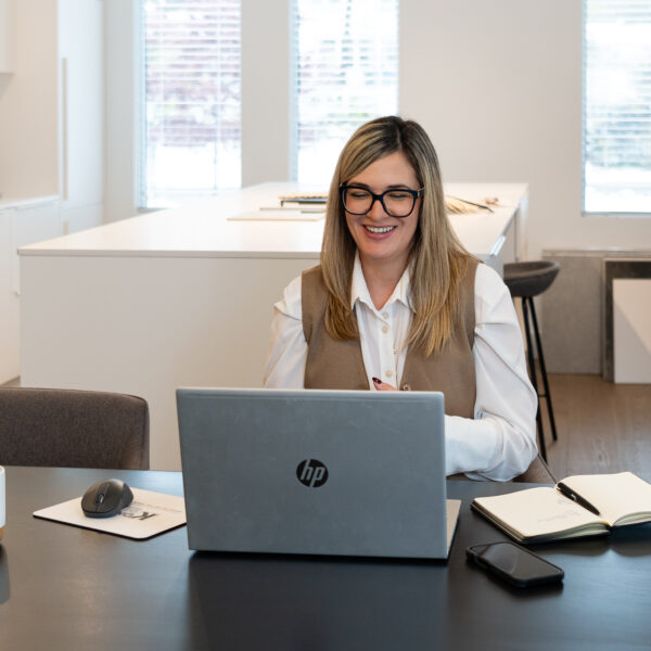 femme souriante devant comptoir de matériaux et de couleurs, designer, laptop