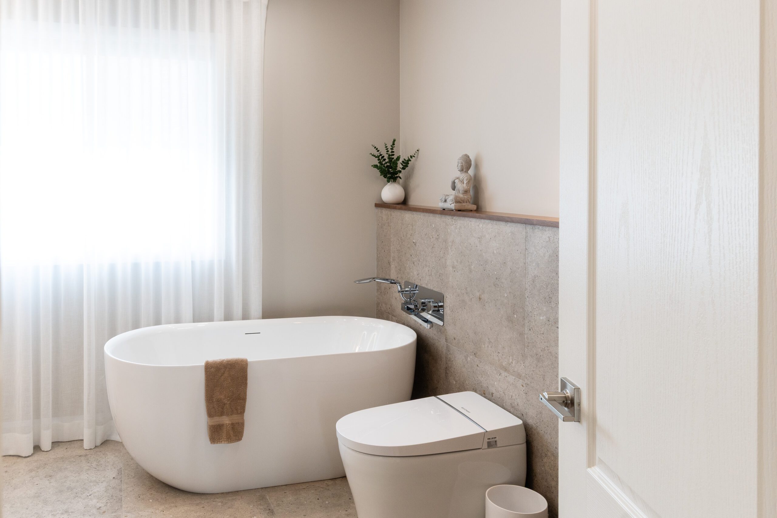 Baignoire blanche ovale avec tablettes et décorations dans une salle de bain moderne