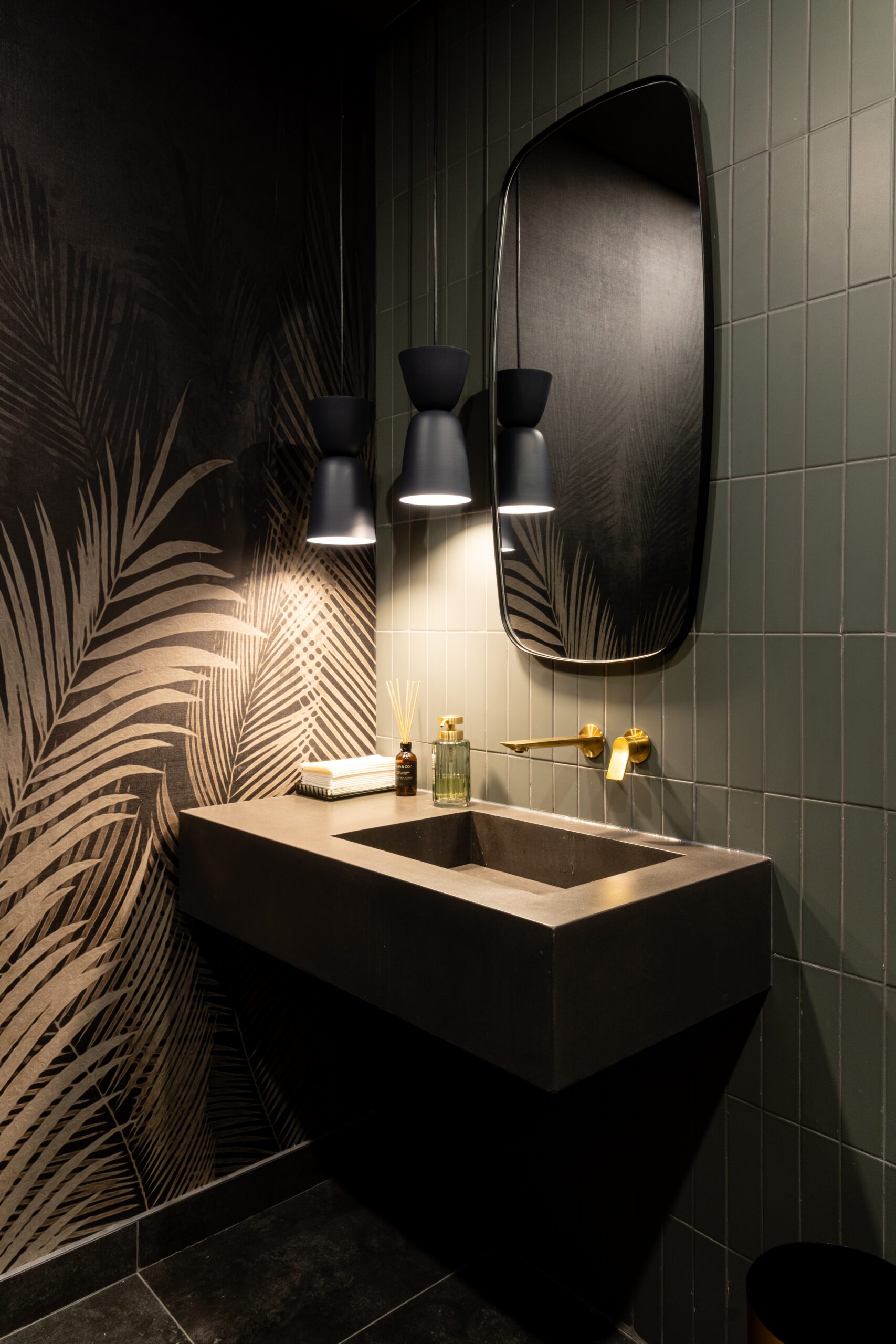 salle de bain sombre vintage avec mur de céramique vert foncé, lumières tamisées noires