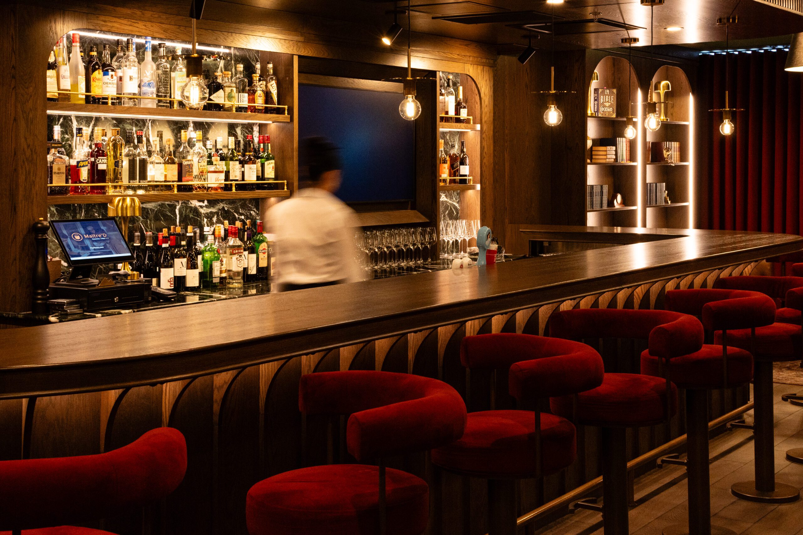 restaurant tamisé moderne , bar avec serveur, bouteilles de boissons et verres