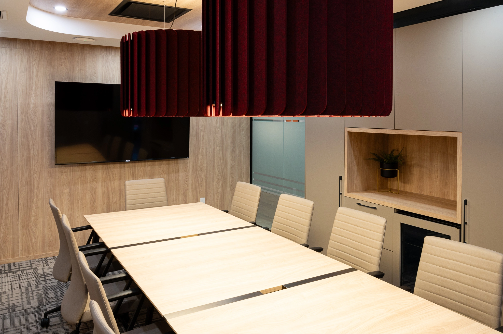 Salle de conférence design moderne, lampes suspendues rouge bourgognes. table blanche avec fauteuils blancs.