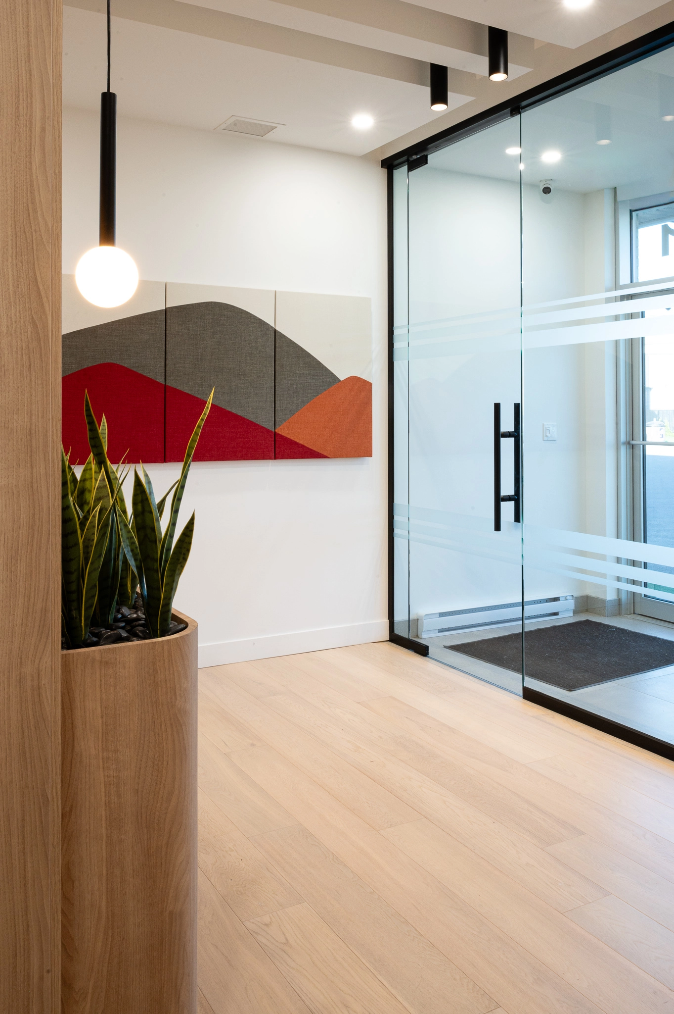 Bureau espace professionnel Parmofab avec enseigne blanche vitrée et plante verte. Cadre mural de formes géométriques colorées.